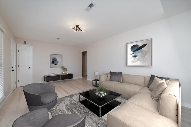 living area featuring baseboards, visible vents, and light wood-style floors