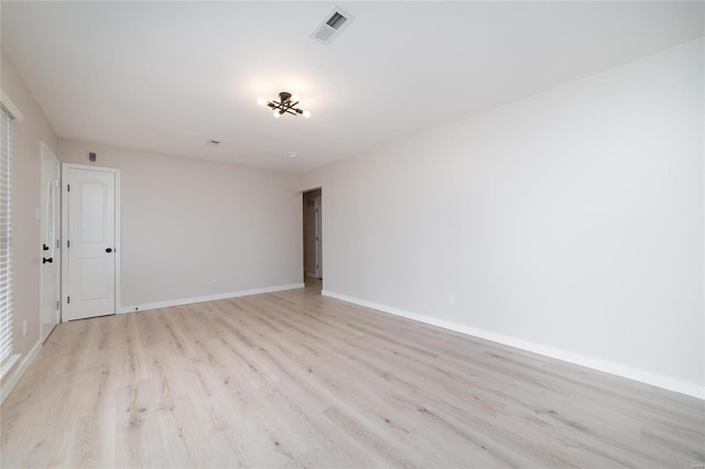 unfurnished room featuring light wood-type flooring, visible vents, and baseboards