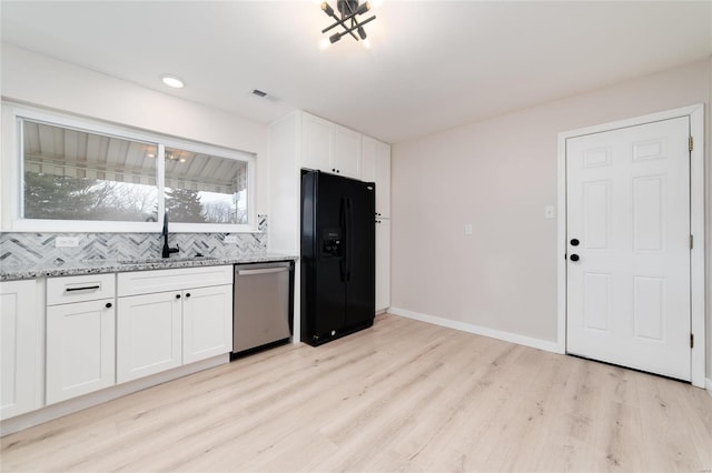 kitchen featuring visible vents, black fridge with ice dispenser, light stone counters, stainless steel dishwasher, and a sink