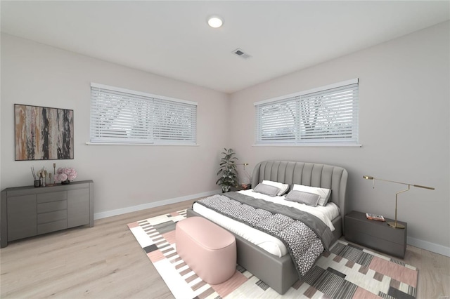 bedroom featuring light wood-type flooring, visible vents, and baseboards