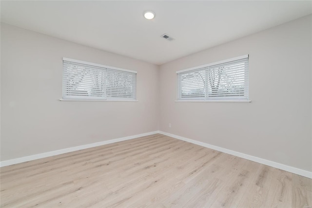 spare room with light wood-style floors, visible vents, and baseboards