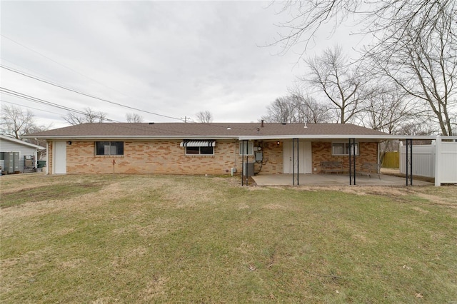 rear view of property with a lawn, a patio, roof with shingles, fence, and brick siding