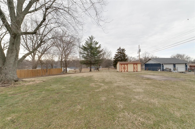 view of yard featuring an outbuilding, a storage unit, and fence