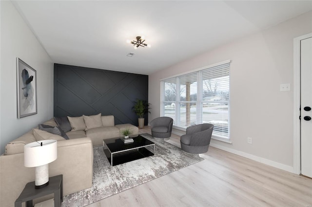 living area featuring an accent wall, wood finished floors, and baseboards