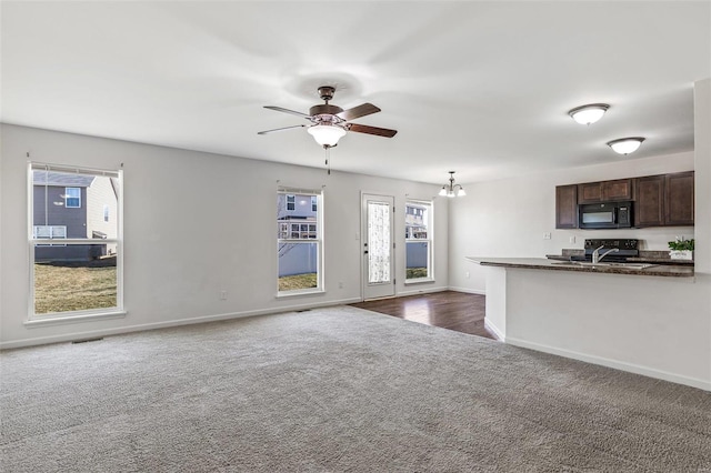 kitchen with dark colored carpet, dark countertops, dark brown cabinets, black microwave, and baseboards