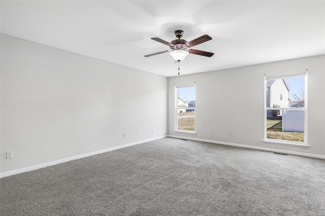 carpeted spare room featuring visible vents, baseboards, and a ceiling fan