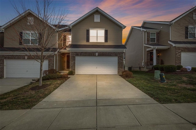 traditional-style house with a garage, concrete driveway, and brick siding