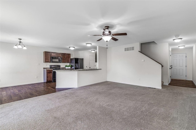 unfurnished living room with baseboards, visible vents, dark colored carpet, and ceiling fan with notable chandelier