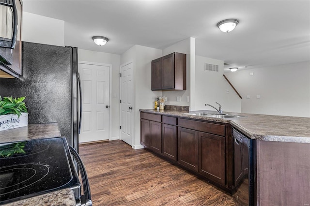 kitchen with visible vents, dark wood finished floors, a peninsula, black appliances, and a sink