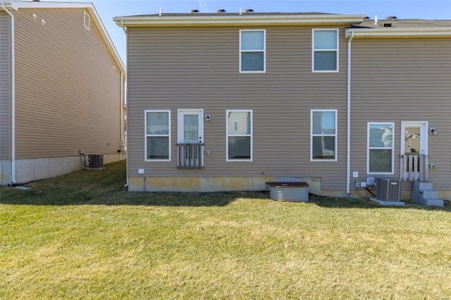 back of property featuring central AC unit and a lawn