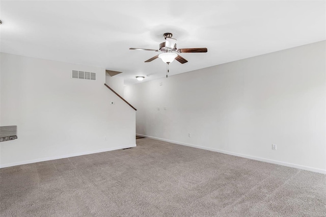 carpeted empty room featuring a ceiling fan, visible vents, and baseboards