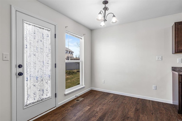 unfurnished dining area featuring dark wood-style floors, a chandelier, visible vents, and baseboards