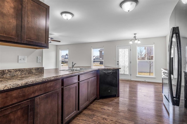 kitchen featuring a peninsula, a sink, black dishwasher, dark wood-style floors, and dark countertops