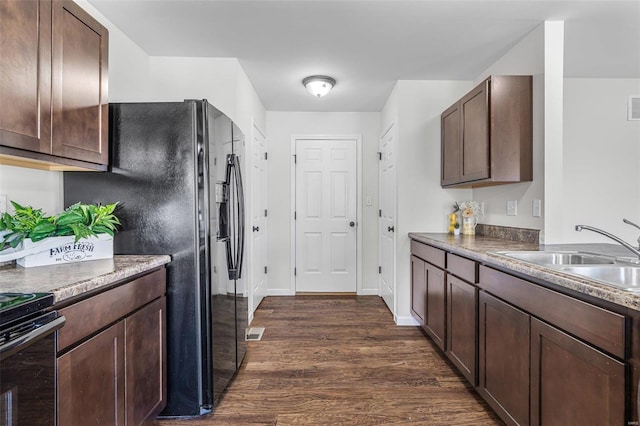 kitchen with dark brown cabinetry, dark wood finished floors, a sink, and black fridge with ice dispenser