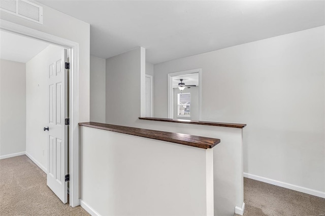 corridor with an upstairs landing, carpet, visible vents, and baseboards