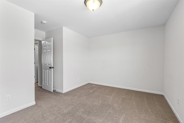 spare room featuring carpet flooring and baseboards