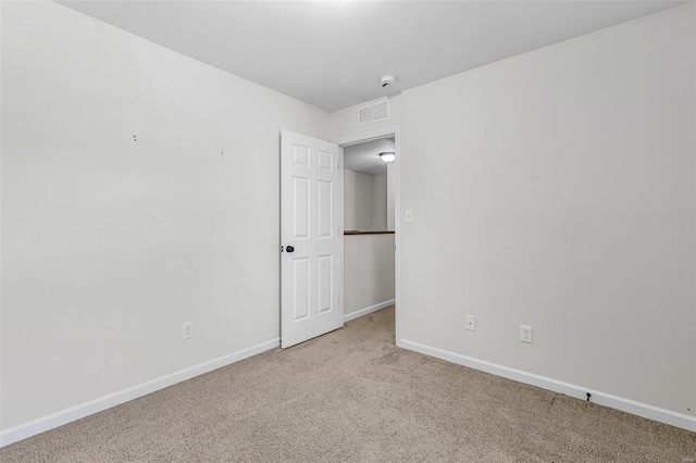 carpeted spare room with visible vents and baseboards