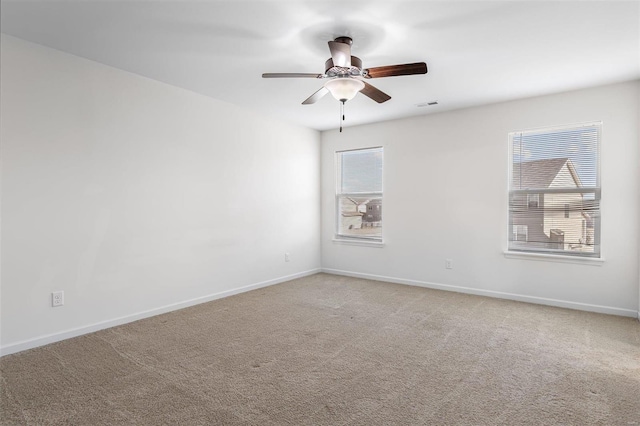 empty room featuring light carpet, plenty of natural light, visible vents, and baseboards