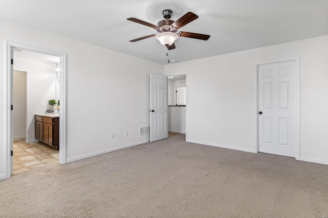 unfurnished bedroom featuring light carpet, ensuite bath, visible vents, and baseboards