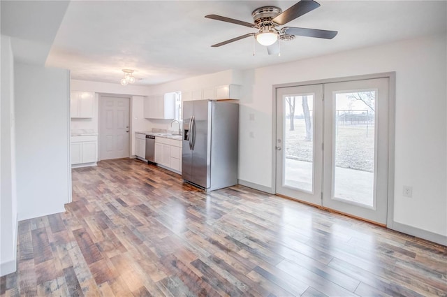 kitchen with stainless steel appliances, light countertops, white cabinets, a sink, and light wood-type flooring