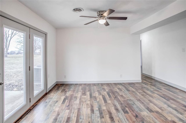 unfurnished room with wood finished floors, visible vents, and baseboards