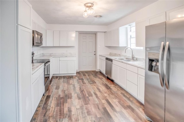 kitchen featuring stainless steel appliances, light wood-style floors, white cabinets, and a sink