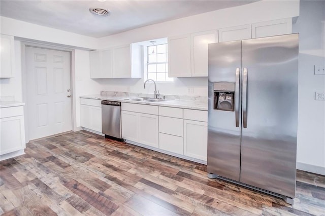 kitchen featuring appliances with stainless steel finishes, light countertops, a sink, and white cabinetry