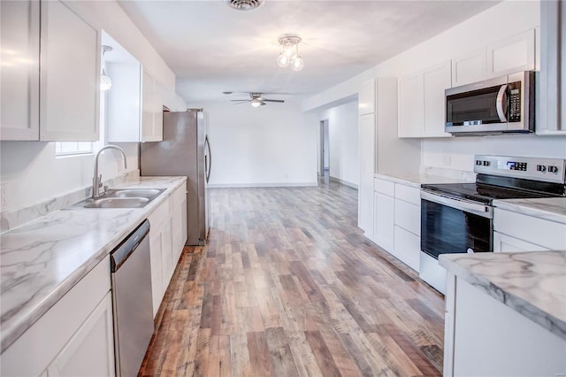 kitchen with appliances with stainless steel finishes, white cabinets, ceiling fan, and light wood-style flooring