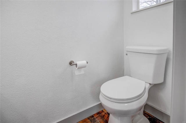 bathroom with wood finished floors, toilet, and baseboards