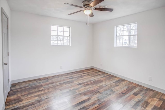 spare room with plenty of natural light, baseboards, and dark wood finished floors