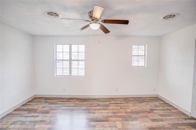 empty room featuring wood finished floors, visible vents, and baseboards