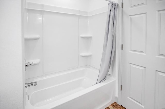 bathroom featuring wood finished floors and shower / bath combo with shower curtain