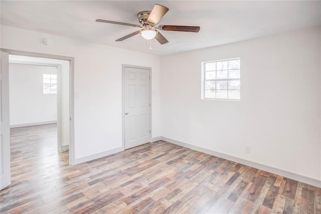 unfurnished bedroom with light wood-type flooring, ceiling fan, and baseboards