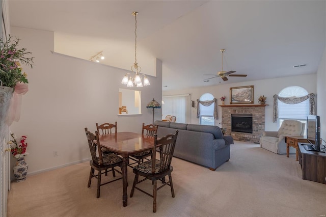 dining room featuring light carpet, baseboards, a ceiling fan, lofted ceiling, and a brick fireplace