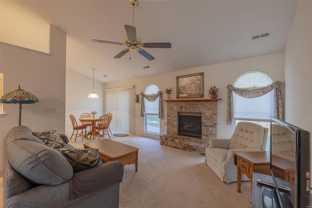 carpeted living area with a ceiling fan, visible vents, plenty of natural light, and a fireplace