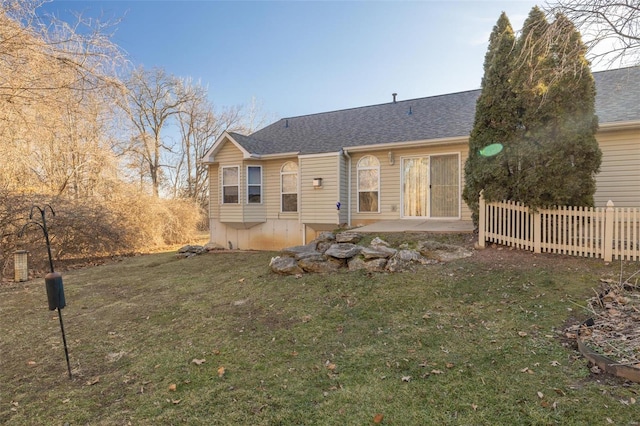 rear view of house featuring a shingled roof, fence, a lawn, and a patio