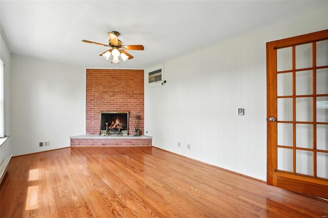 unfurnished living room featuring a brick fireplace, a ceiling fan, and wood finished floors