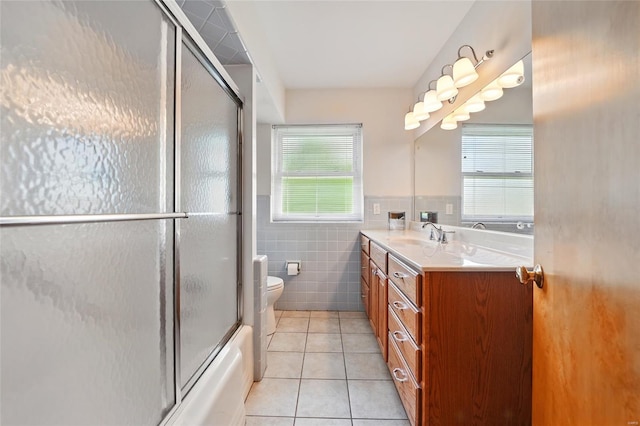 bathroom featuring tile walls, tile patterned flooring, vanity, toilet, and enclosed tub / shower combo