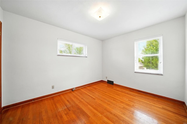 unfurnished room featuring plenty of natural light, light wood finished floors, baseboards, and visible vents