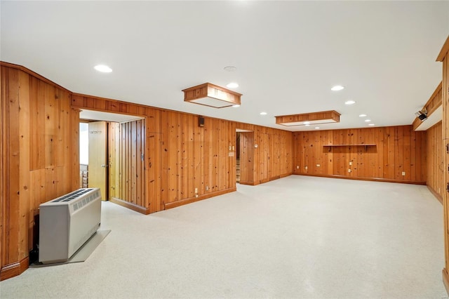 finished basement featuring recessed lighting, heating unit, and wood walls