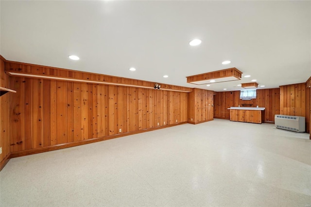 below grade area featuring wooden walls, recessed lighting, and heating unit