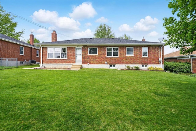 rear view of property featuring brick siding, fence, a yard, and a chimney