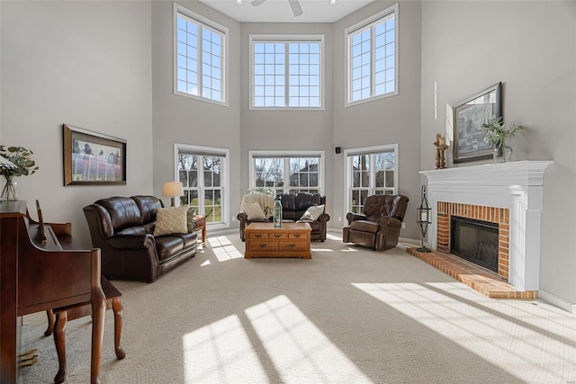 living area featuring ceiling fan, a fireplace, baseboards, and carpet