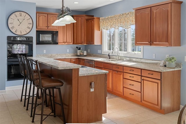 kitchen featuring light stone counters, brown cabinets, a kitchen breakfast bar, black appliances, and a sink