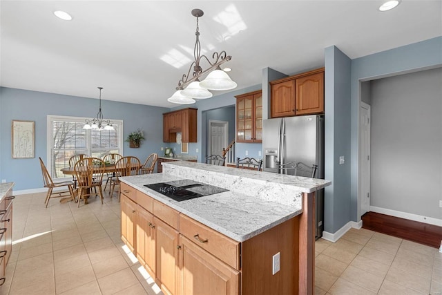 kitchen with a center island, baseboards, black electric stovetop, stainless steel refrigerator with ice dispenser, and light tile patterned flooring