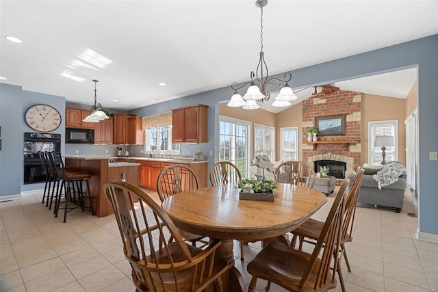 dining space featuring a brick fireplace, baseboards, lofted ceiling, light tile patterned floors, and recessed lighting