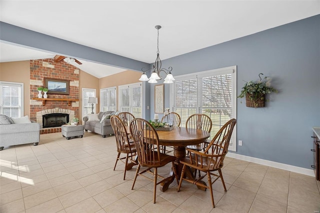 dining space with ceiling fan with notable chandelier, lofted ceiling with beams, a fireplace, light tile patterned floors, and baseboards