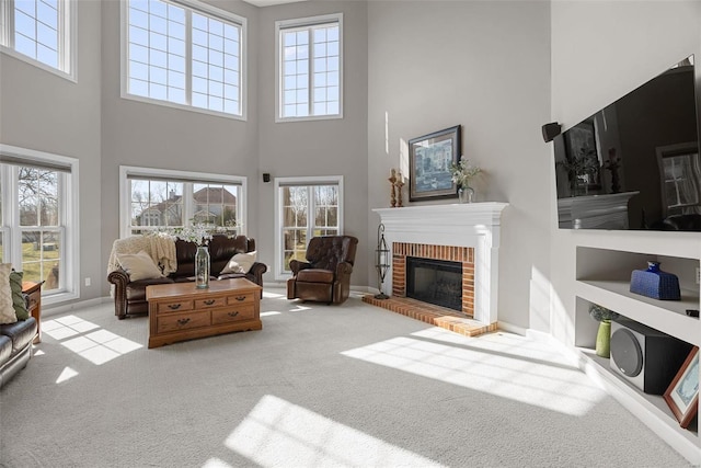 carpeted living area with a wealth of natural light, baseboards, and a brick fireplace