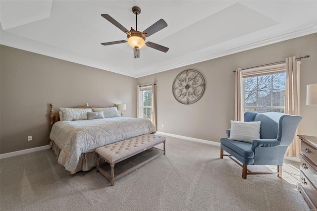 bedroom with light colored carpet, a tray ceiling, and baseboards