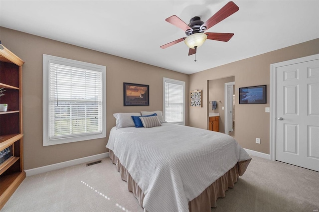 bedroom with visible vents, light carpet, connected bathroom, baseboards, and ceiling fan